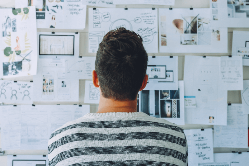 Man looking a wall filled with documents